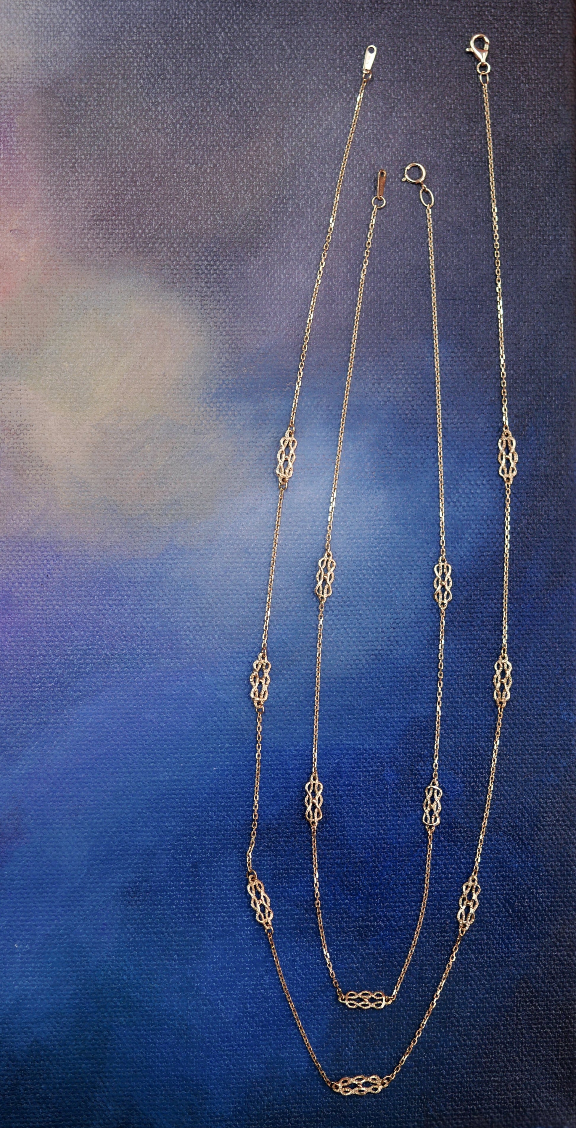 Gold chain necklace on a textured blue background